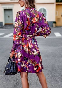 Vista posteriore vestito floreale viola con maniche a sbuffo e elegante cintura in vita