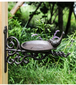 Close-up of vintage cast iron bird feeder wall decor with rustic bird and scroll bracket