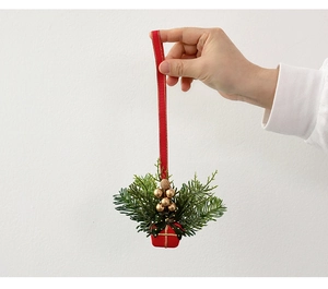 Detail of Christmas gift box hanging ornament with red ribbon held by hand