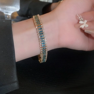 Elegant gold bracelet with intertwined white and blue crystals on a female wrist