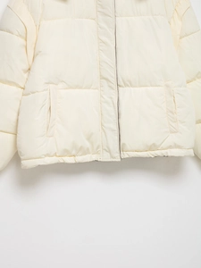 Detail of cream quilted cotton jacket showing front closure and side pockets