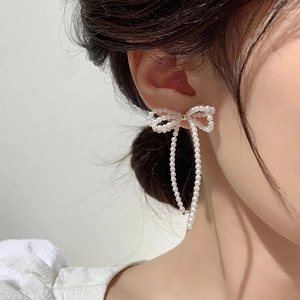 Elegant bow-shaped pearl tassel earrings with silver needle on female model