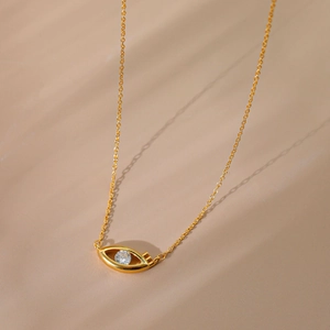 Elegant gold-plated sun bow necklace with evil eye pendant and crystal on textured surface