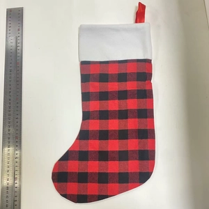 Detail of red and black buffalo plaid Christmas stocking with white faux fur trim and ruler