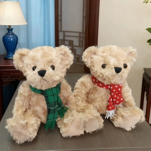 Plush teddy bears in warm beige with plaid and snowflake scarves on wooden surface