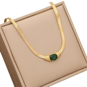 Elegant golden herringbone necklace with emerald gemstone in a beige jewelry box