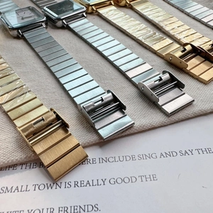 Close-up of elegant square quartz watches with polished metal link bands and folding clasps