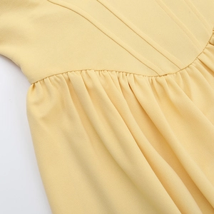 Detail of light yellow strapless dress showing waist tailoring and pleated chiffon texture
