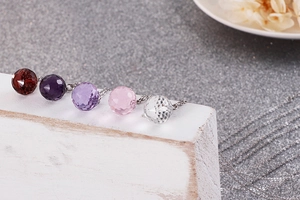Detailed view of five faceted crystal ball pendants in red, purple, and pink on O-chains