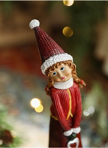 Close-up of a resin Christmas girl figurine with realistic knit texture and festive bokeh