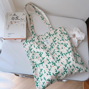 Detailed macro view of floral cotton tote bag texture with green leaves and orange flowers