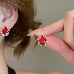 Detail of 18k gold plated stud earrings with red oval gemstone and zircon butterflies