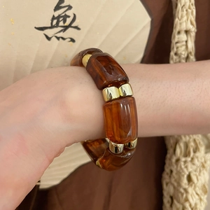 Detail of amber resin geometric wide bracelet with golden metal spacers on wrist