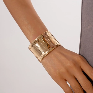 Close-up of a wide golden geometric cuff bracelet on a model's wrist for a chic style