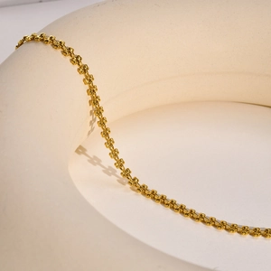 Macro detail of golden wheat chain necklace showing 3D heart-shaped links and texture