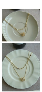 Detail of double-layered gold necklace with pearls, brown beads and zircon pendant