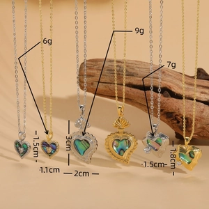 Golden heart necklaces with rainbow abalone shell and zircons on wooden background
