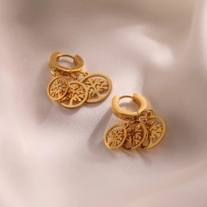 Gold plated titanium steel hoop earrings with cutout tree of life pendant on silk background
