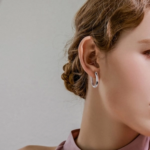 Close-up of a minimalist silver hoop earring with opal inlay worn by a female model