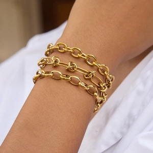 Detailed view of layered 18k gold plated titanium steel chain bracelets on a wrist