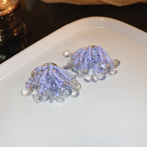 Gros plan de boucles d'oreilles fleuries en perles mauves avec pendentifs en cristal facetté