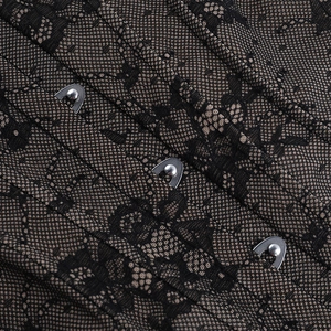 Detailed close-up of lace corset with silver metal hook-and-eye closures and intricate fabric