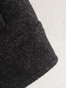 Detailansicht der schwarzen Tweed-Stoffstruktur und präzisen Nähte der Modejacke