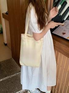 Detail of cream canvas tote bag featuring brown HAPPY lettering print in a cafe setting
