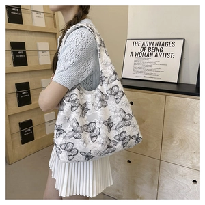 Detail of a white fluffy tote bag with black butterfly embroidery in a lifestyle setting