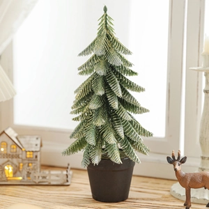 Miniature flocked Christmas tree with gold glitter tips in a black pot for desk decor