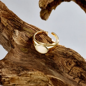 Close-up of a 14k gold plated signet ring with an adjustable open band on wood