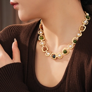 Détail de collier vintage avec perles et pierres ambrées sur cadre ajouré doré