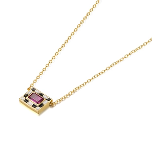 Macro detail of gold pendant with purple gemstone and black-white enamel patterns