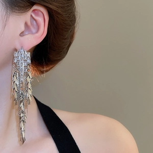 Close-up of elegant silver tassel earrings with zircons and leaf charms on a model