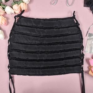 Detail of black quilted puffer mini skirt with adjustable side lacing on pink background