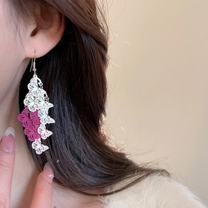 Detail shot of long butterfly tassel earrings in pink and white with heart accents