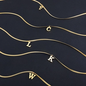 Golden snake chain necklaces with 18K gold-plated initial pendants on black background