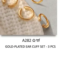 Detail of minimalist gold plated C-shaped ear cuffs on white knitted fabric
