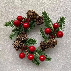 Detailed close-up of mini Christmas wreath with artificial pine branches, cones and red berries