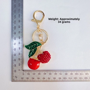 Macro view of cherry keychain with rhinestones next to a scale ruler for size reference