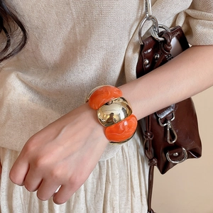 Close-up of chunky orange resin beads and large gold metal ball on elastic bracelet