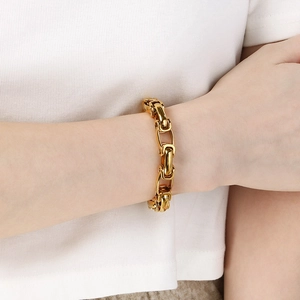 Bracelet à maillons gourmette dorés pour hommes et femmes porté sur un fond de tricot blanc