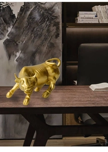 Detailed close-up of golden bull figurine with muscular lines on wooden office desk