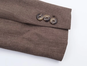 Détail de la manche d'une veste marron avec trois boutons marbrés et tissu texturé