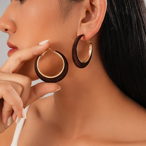 Flocked geometric round earrings in dark brown and gold worn by a model in close-up