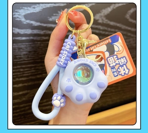 Detail of lavender cat paw keychain with CAT STORY silicone pendant and matching hand strap
