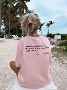 Détail d'un t-shirt rose en coton avec imprimé de lettres noires sur la plage