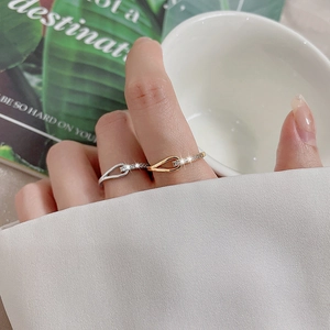 Close-up of gold and silver interlocking knot rings with pavé cubic zirconia on finger