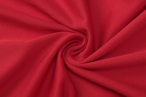 Vue macro du tissu en maille rouge montrant la texture des fibres et le drapé fluide