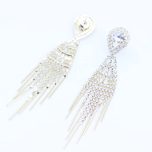Detailed macro view of long golden tassel earrings with sparkling white rhinestones